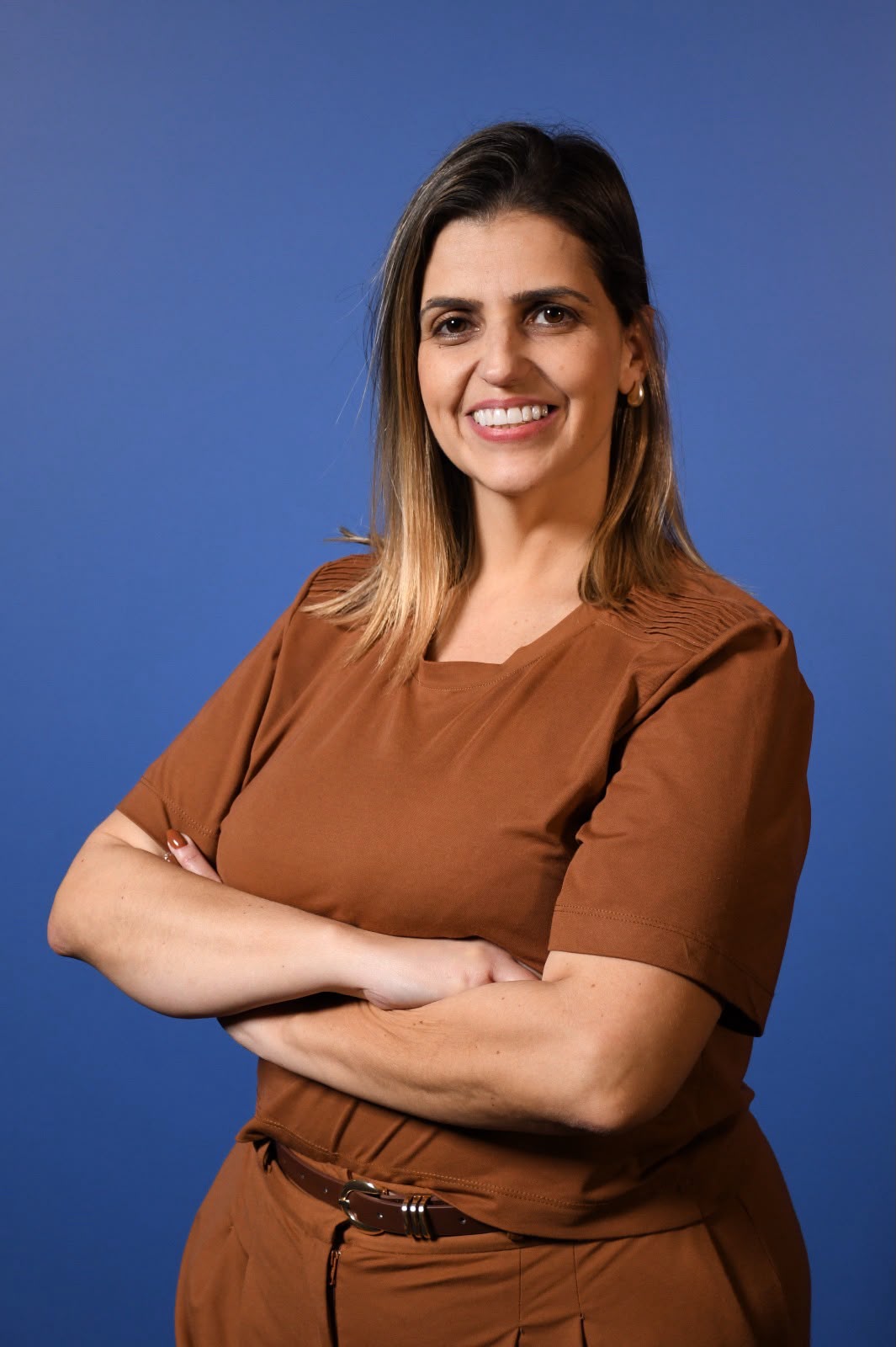 Cristine Rodriguez sorrindo, de braços cruzados